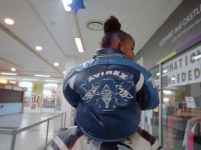 a woman in a blue jacket walking down a hallway