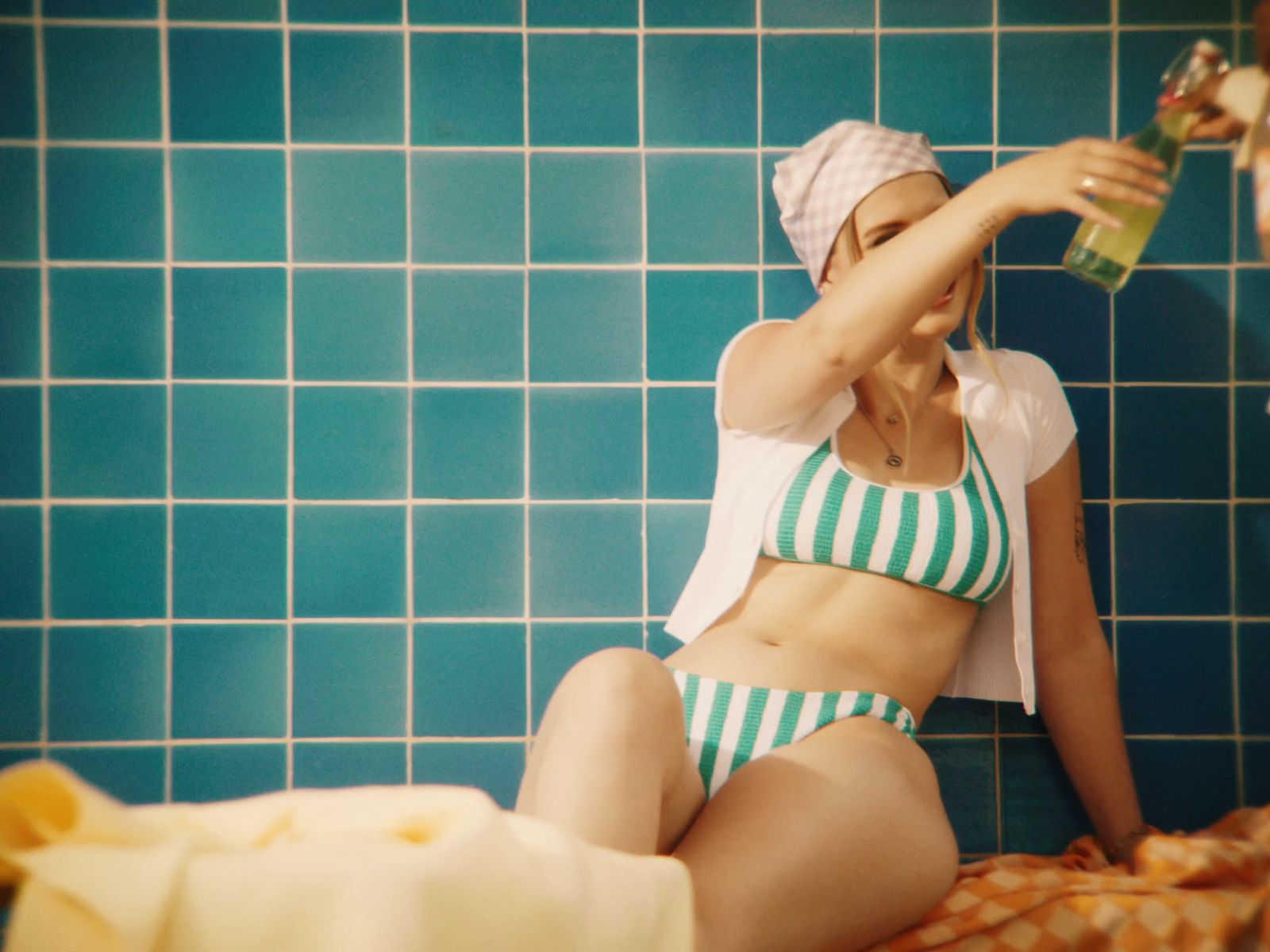 a woman in a bathing suit sitting on a tiled wall