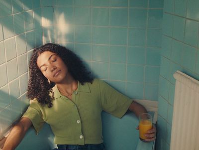 a woman in a green shirt holding a glass of orange juice