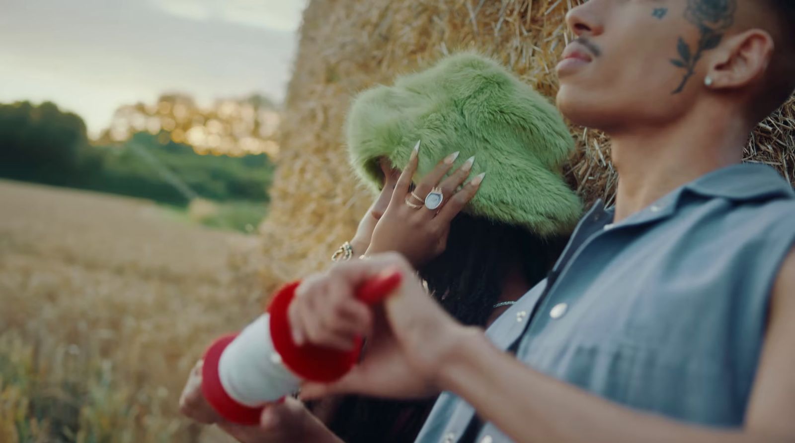 a woman with a green hair and piercings standing next to a hay bale