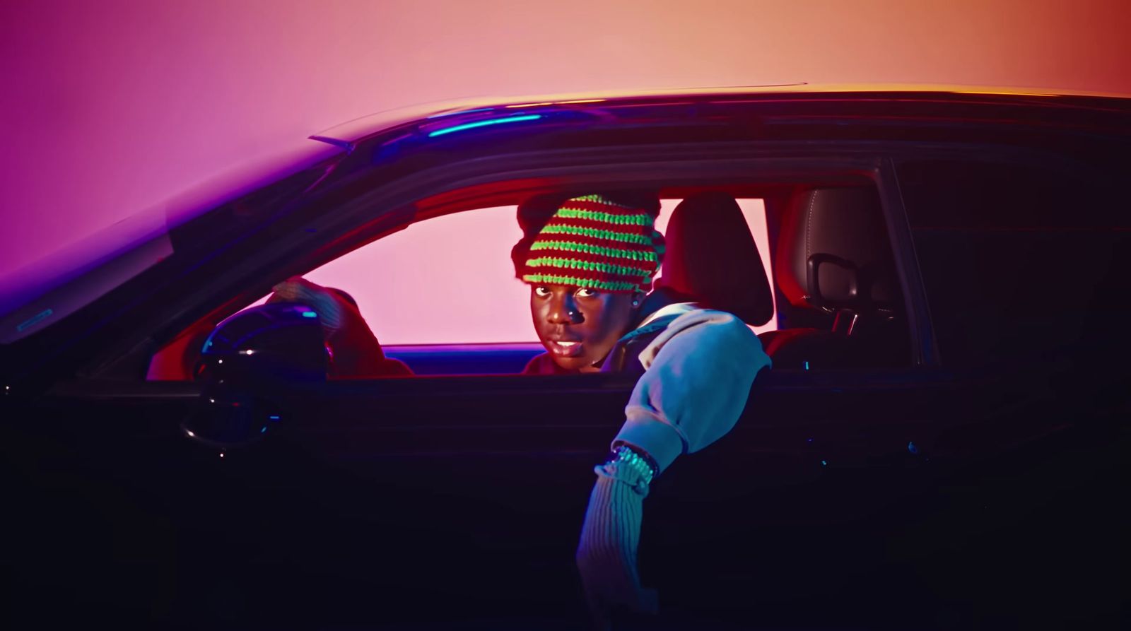 a man sitting in a car with a hat on