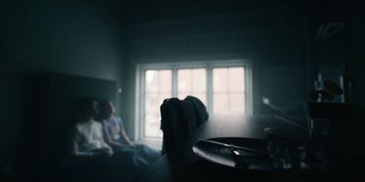 a woman sitting in a dark room next to a window