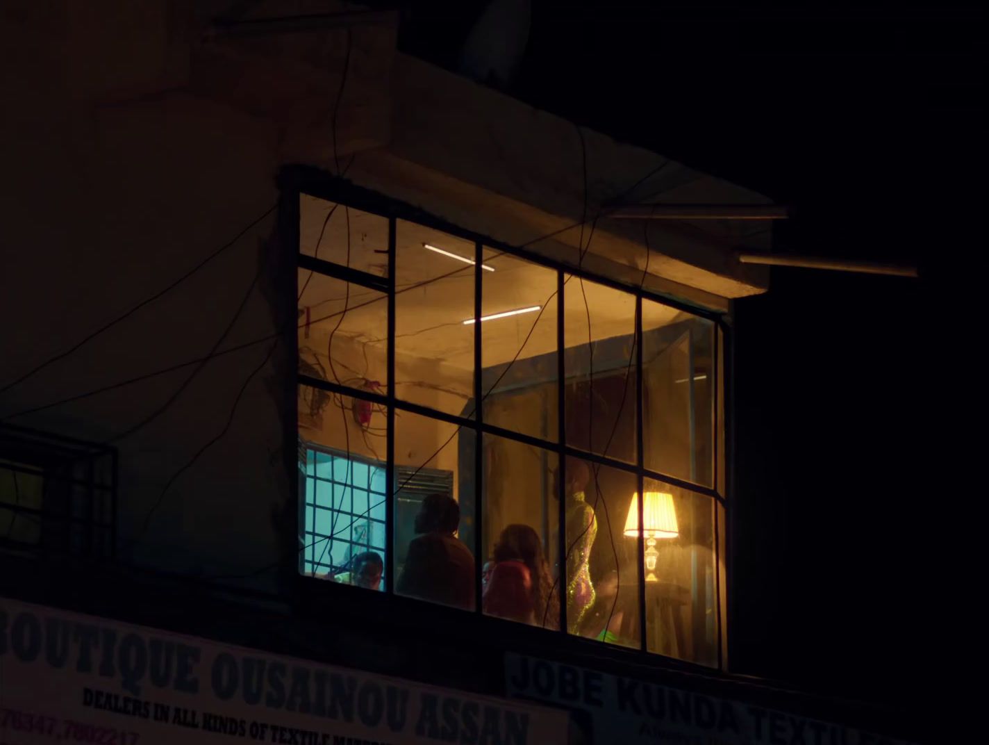 a group of people standing outside of a window at night