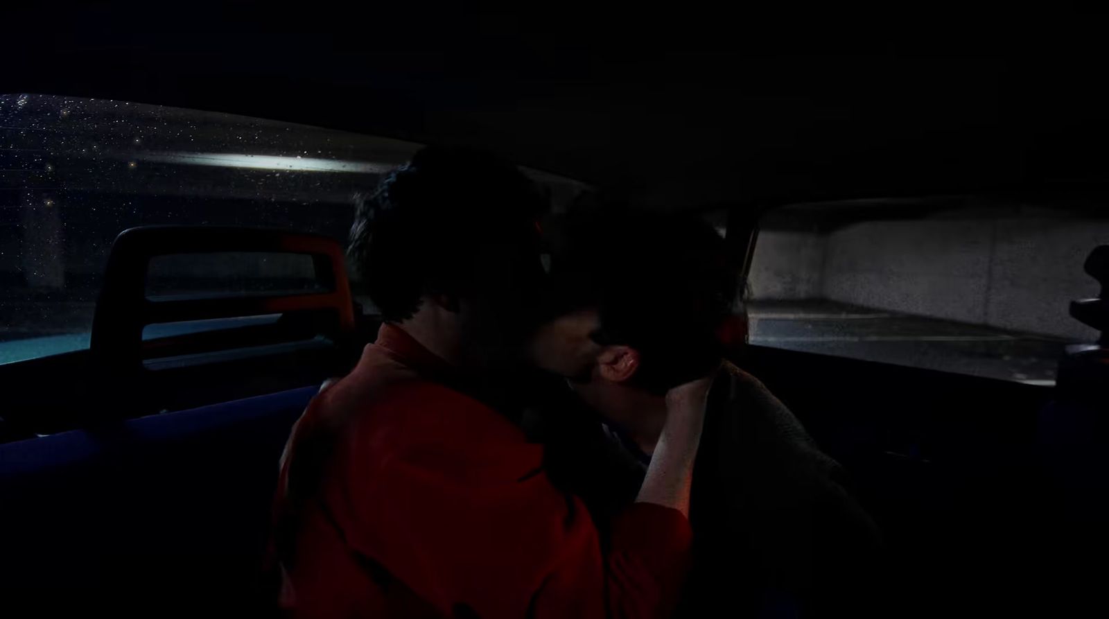 a man and woman kissing in the back of a car