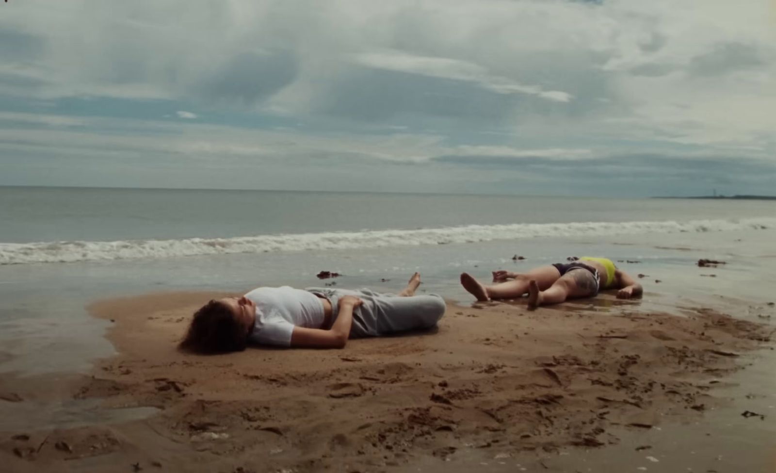 a couple of people laying on top of a sandy beach