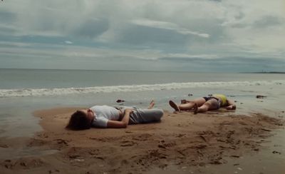 a couple of people laying on top of a sandy beach