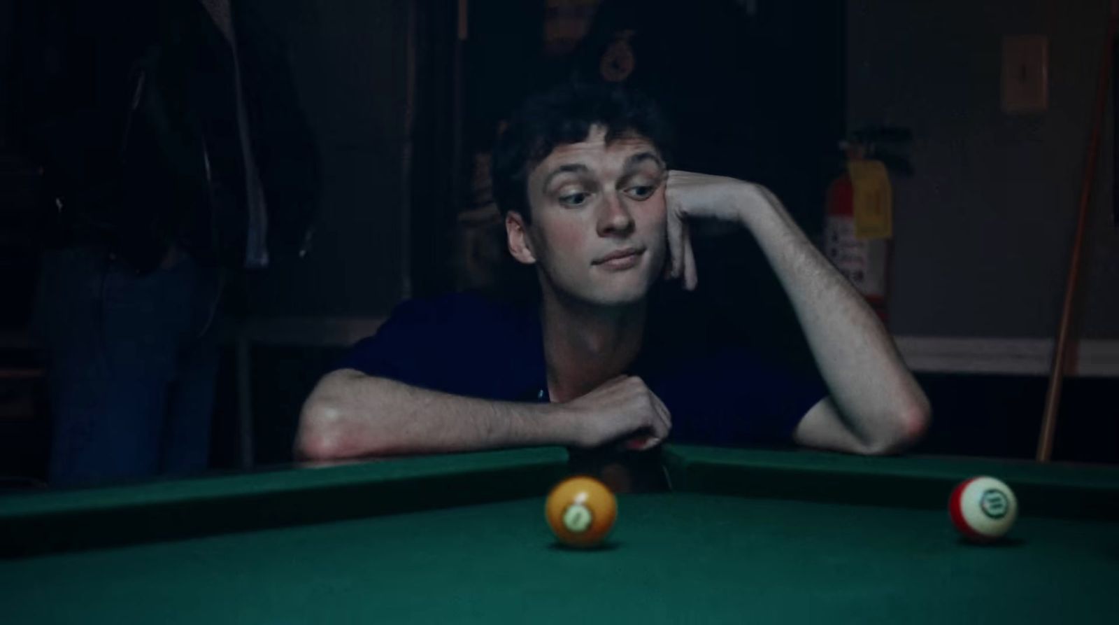 a man leaning on a pool table with a pool ball in front of him