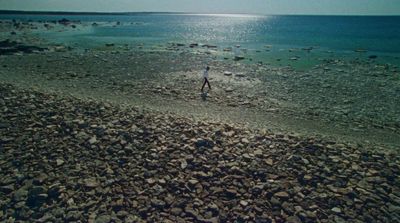 a man standing on a rocky beach next to the ocean