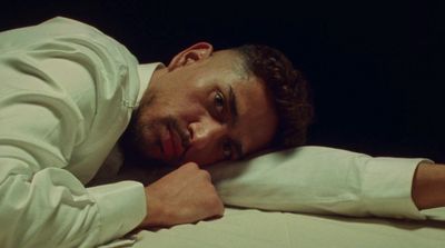 a man laying on top of a bed in a white shirt