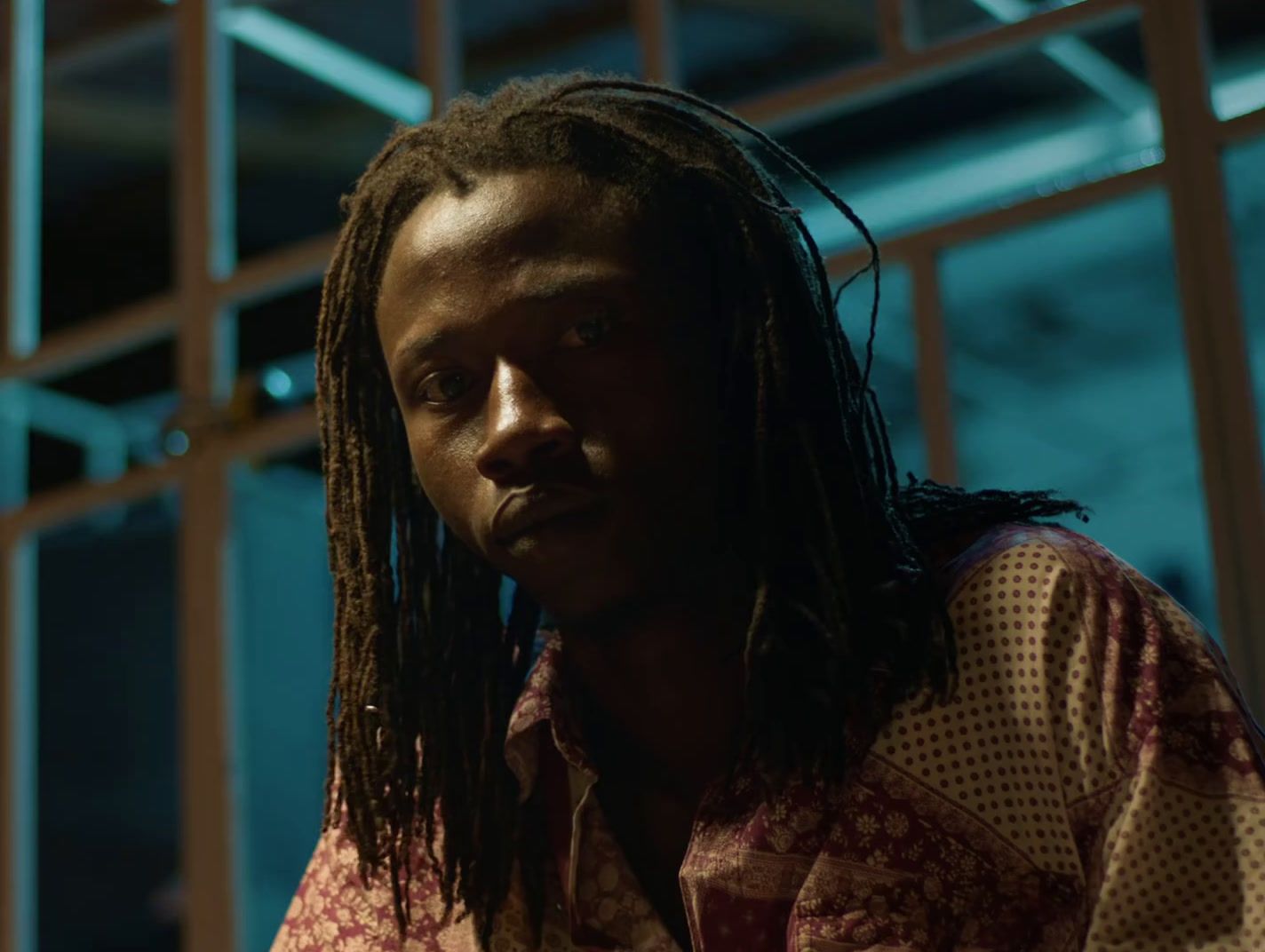 a man with dreadlocks standing in front of a window