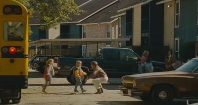 a group of children walking down a street next to a school bus