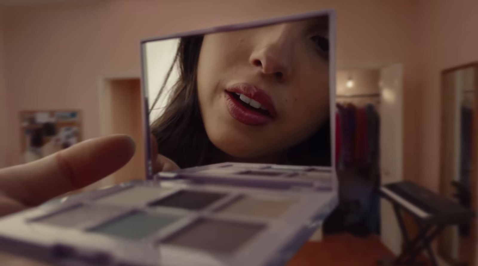 a woman holding a makeup palette in front of a mirror