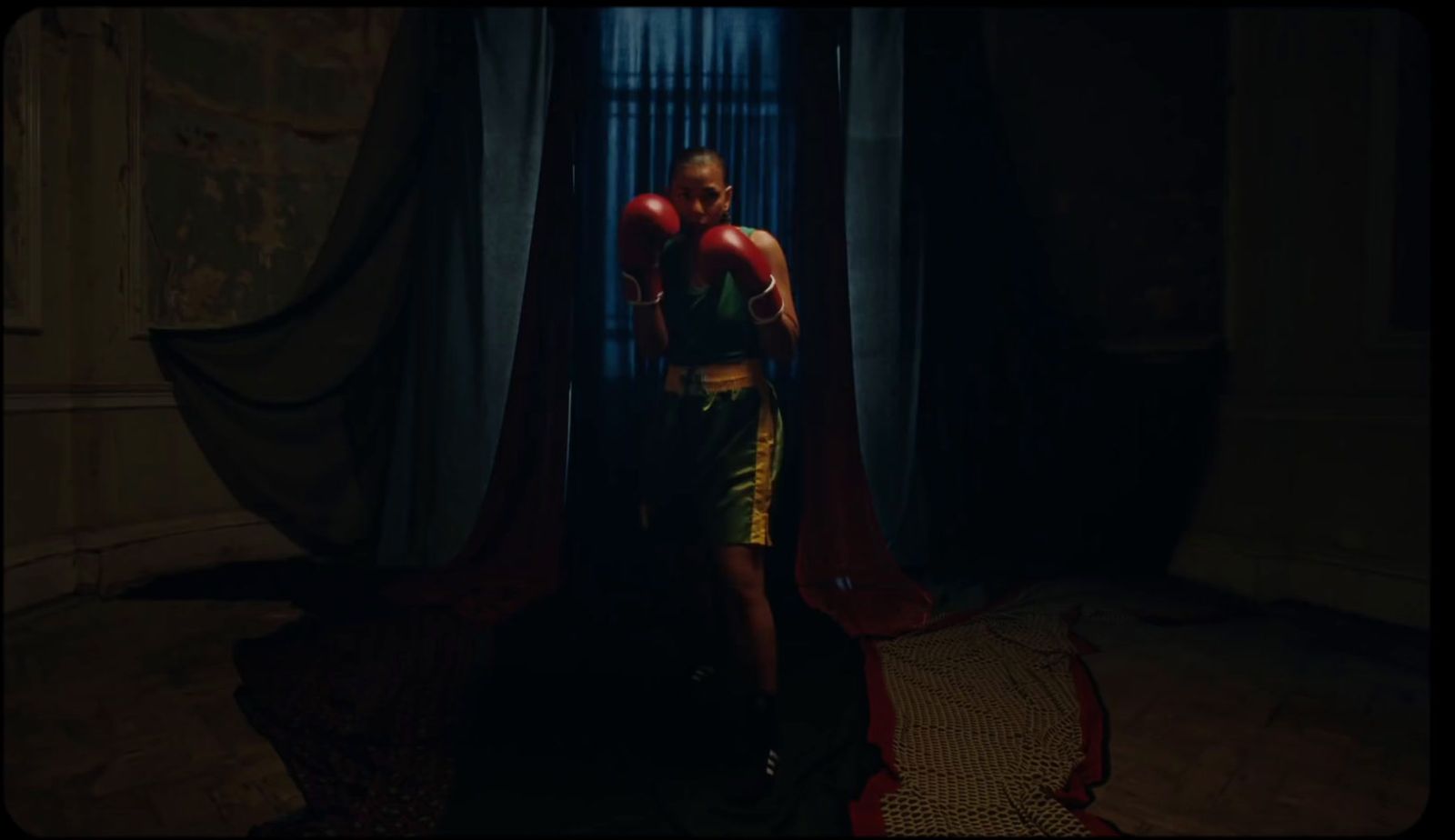 a man standing in a dark room with boxing gloves on