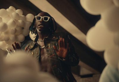 a man wearing sunglasses standing in front of balloons