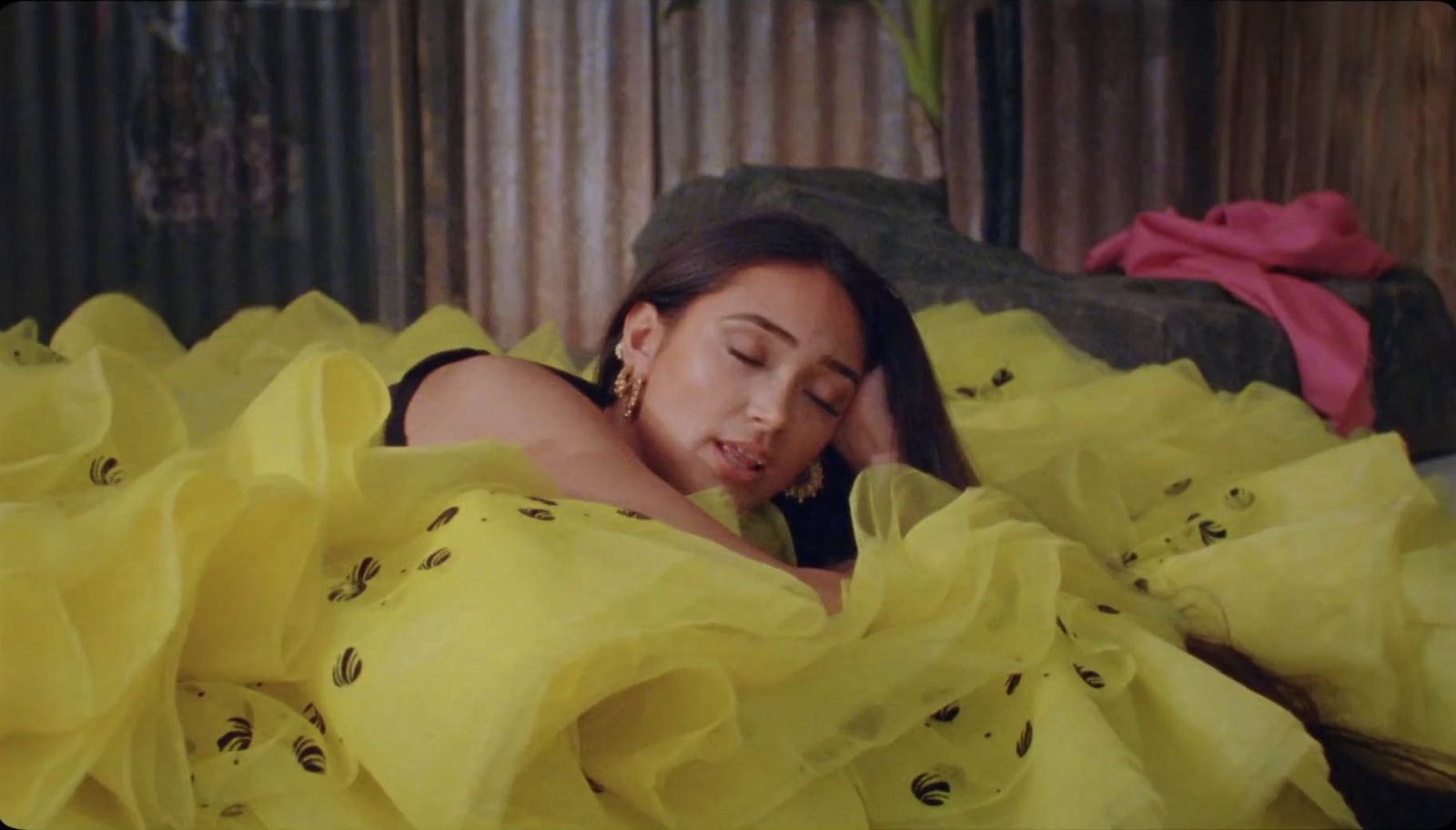 a woman laying in a bed covered in yellow sheets