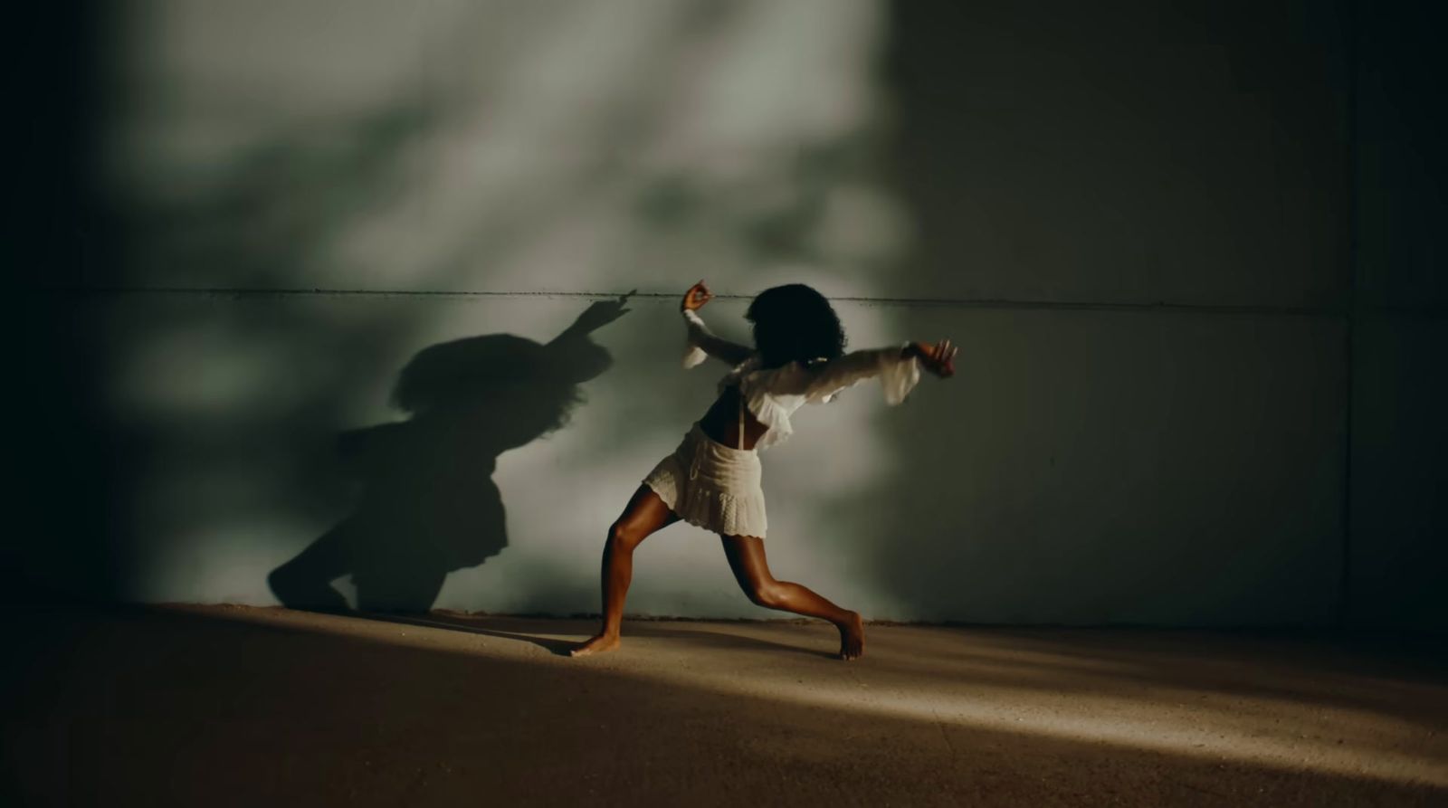 a woman is running in the dark with a shadow on the wall