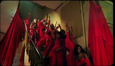 a group of women in red dresses standing on a staircase