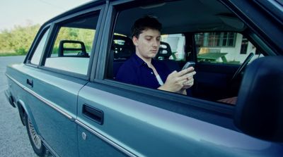 a man sitting in a car looking at his cell phone