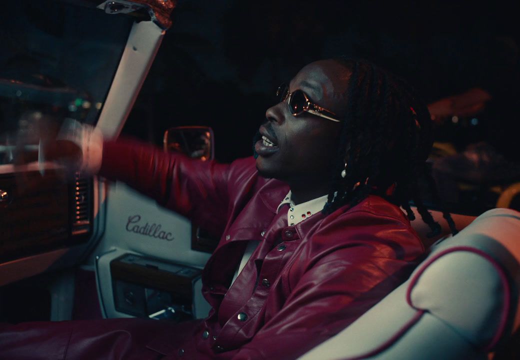 a man in a red leather jacket driving a car