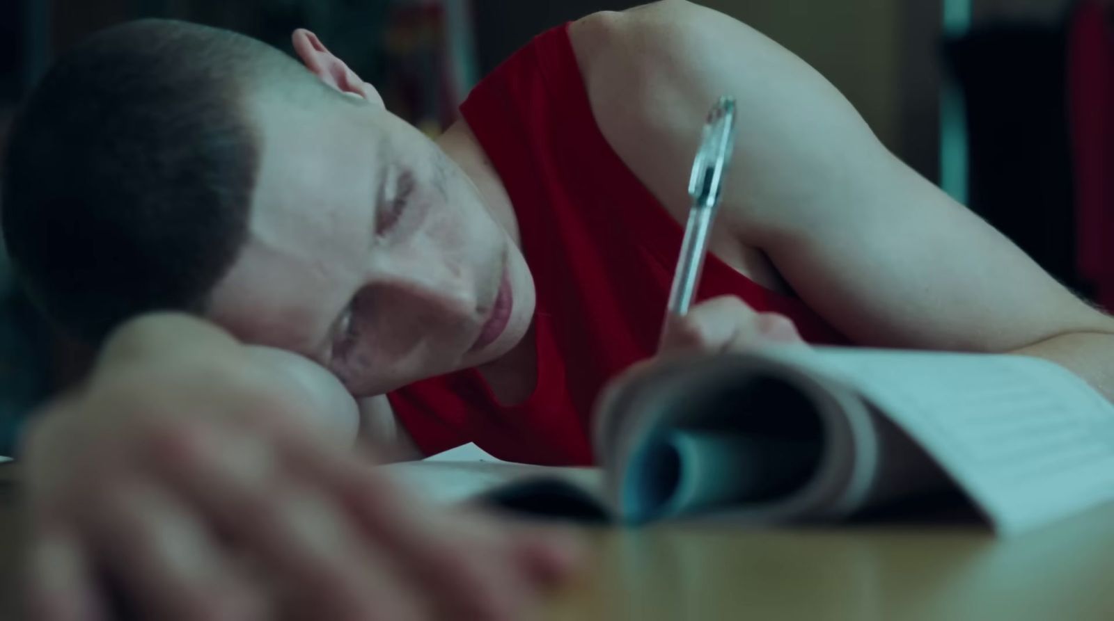 a man in a red shirt writing on a piece of paper