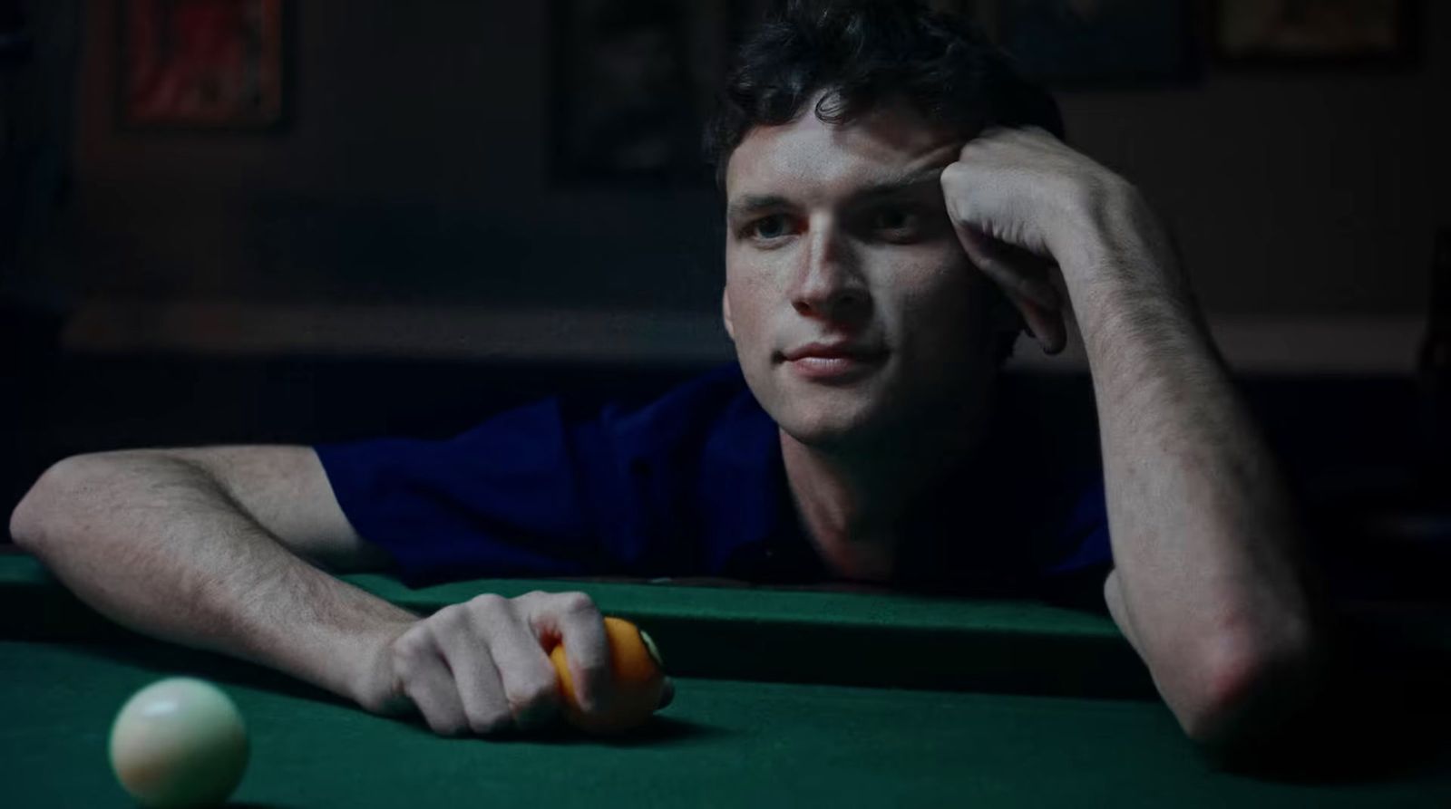 a man sitting at a pool table with a ball in front of him