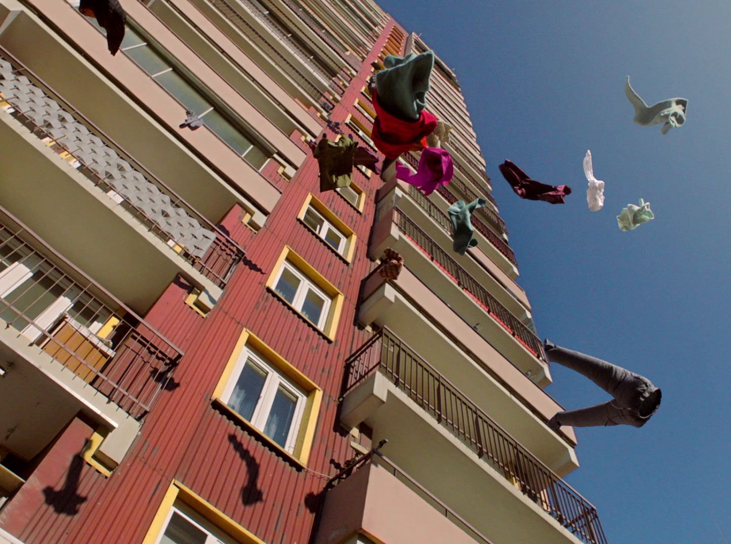 a tall red building with birds flying around it