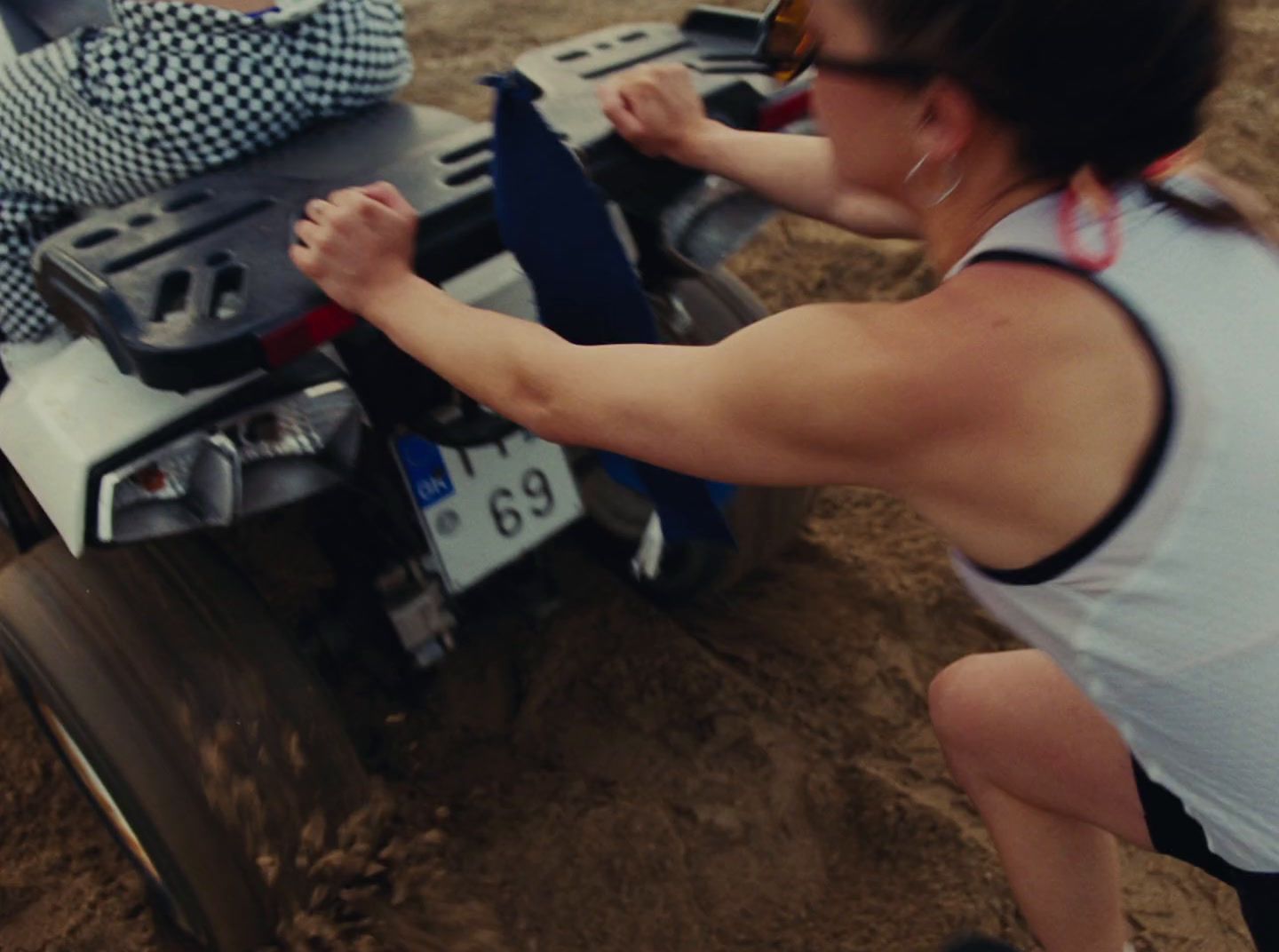 a woman pushing a toy car in the dirt