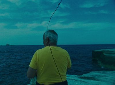 a man in a yellow shirt is flying a kite