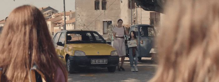 a group of people standing around a yellow car