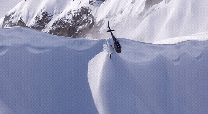 a person skiing down a snowy mountain with mountains in the background