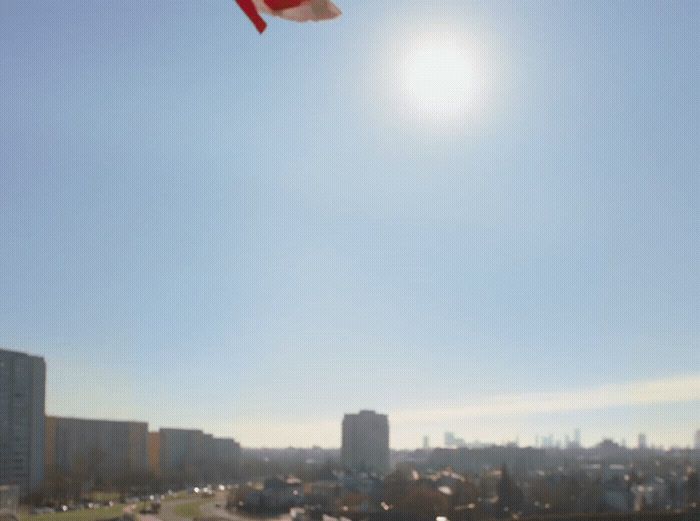 a red and white kite flying over a city