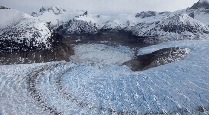 an aerial view of a glacier with mountains in the background