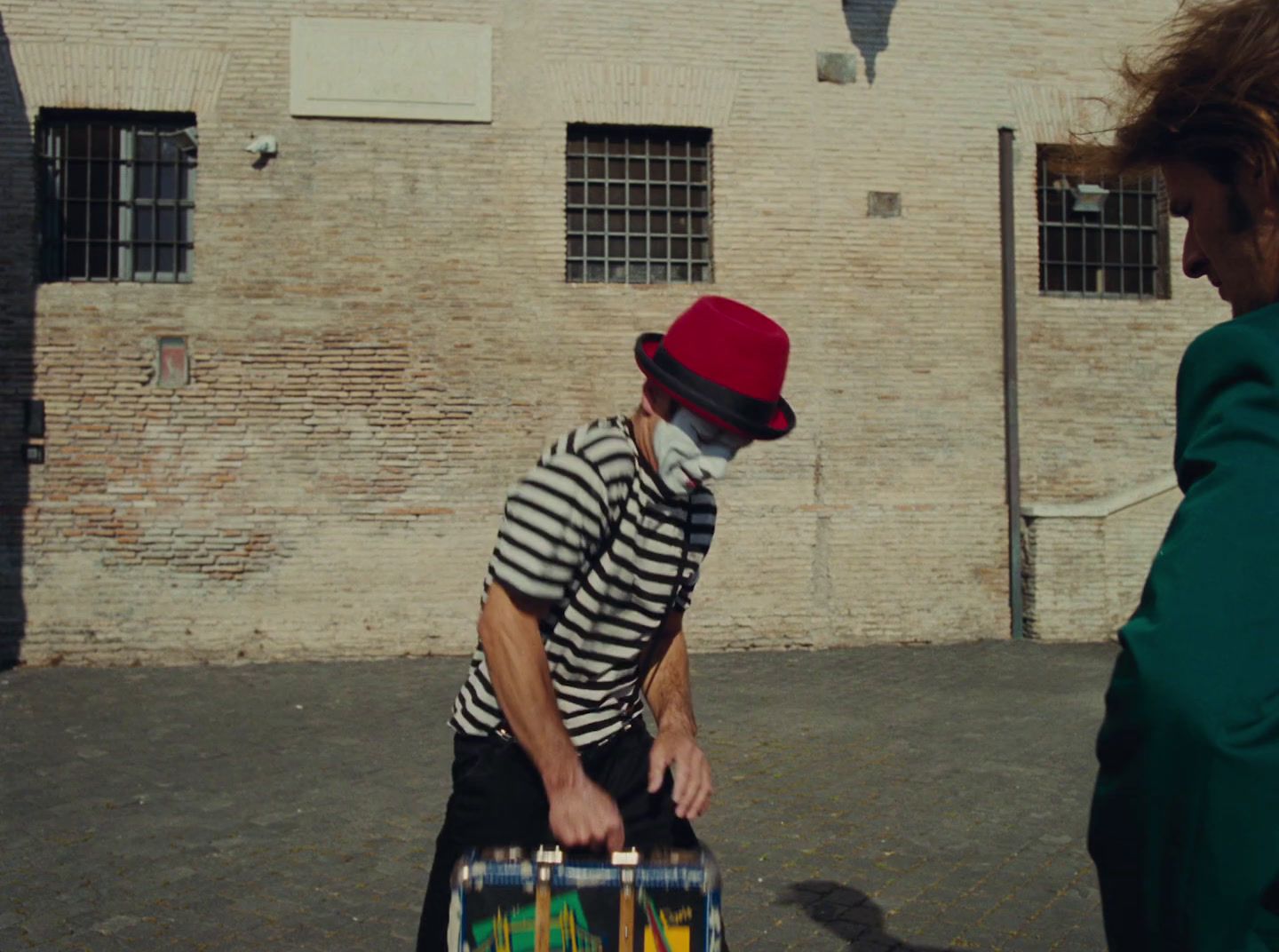 a man in a striped shirt and red hat pulling a suitcase