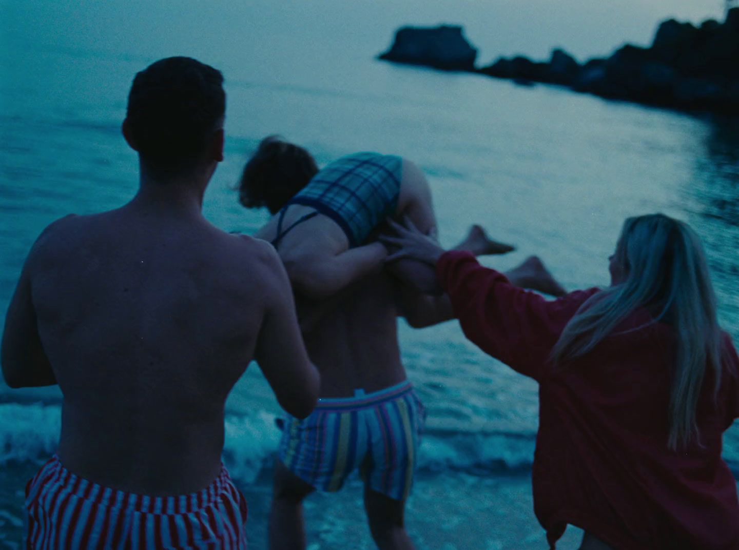 a group of people standing on top of a beach next to the ocean