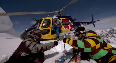 a couple of people sitting in the snow next to a helicopter