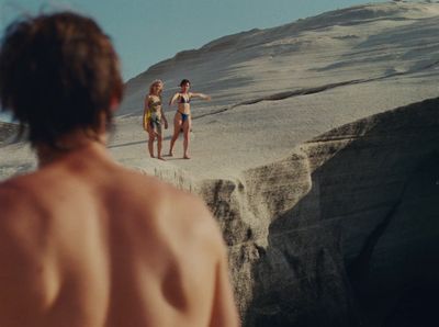 a couple of women standing on top of a sandy beach