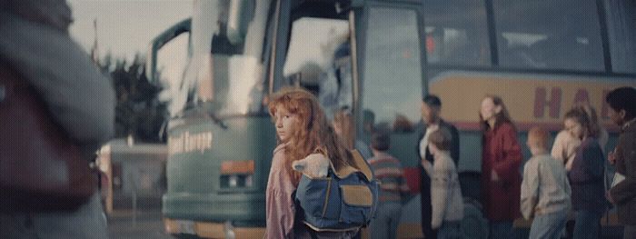 a woman with a backpack standing in front of a bus