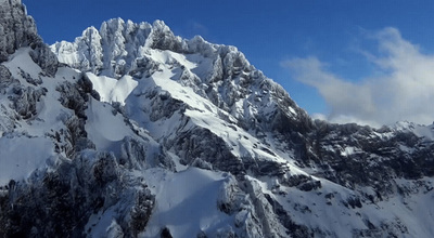 a very tall mountain covered in snow under a blue sky