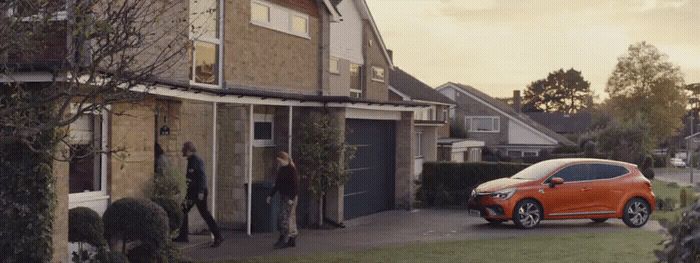 a small orange car parked in front of a house