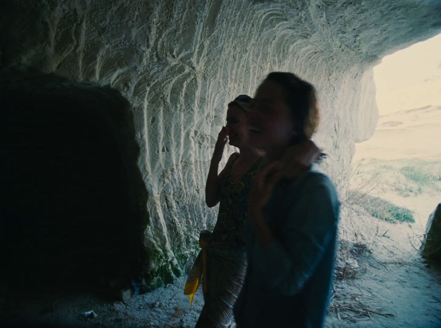 a woman standing in a cave talking on a cell phone