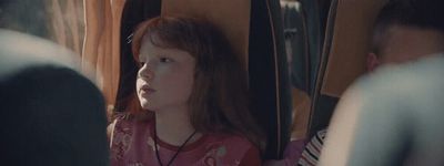 a little girl sitting on a bus looking out the window