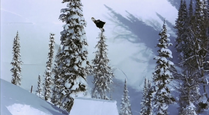 a man flying through the air while riding a snowboard