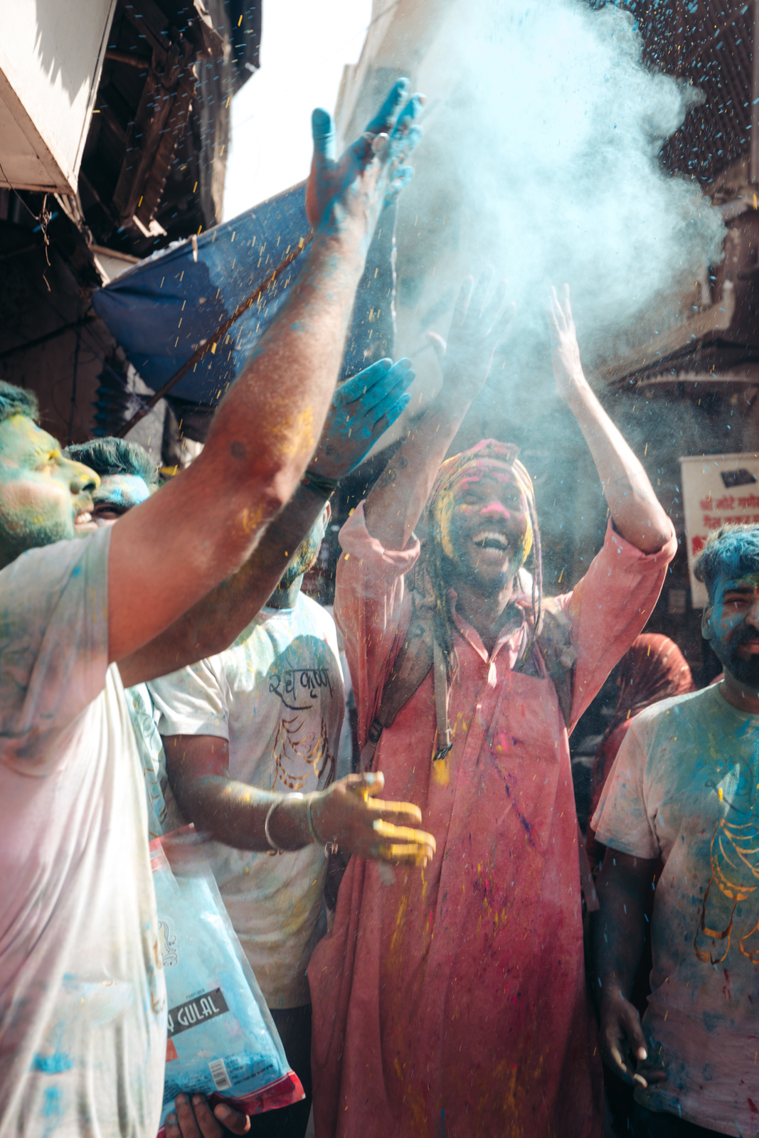 a group of people standing around each other covered in colored powder