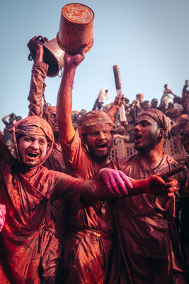 a group of men covered in red paint holding a trophy