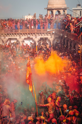 a crowd of people with colored powder and a flag