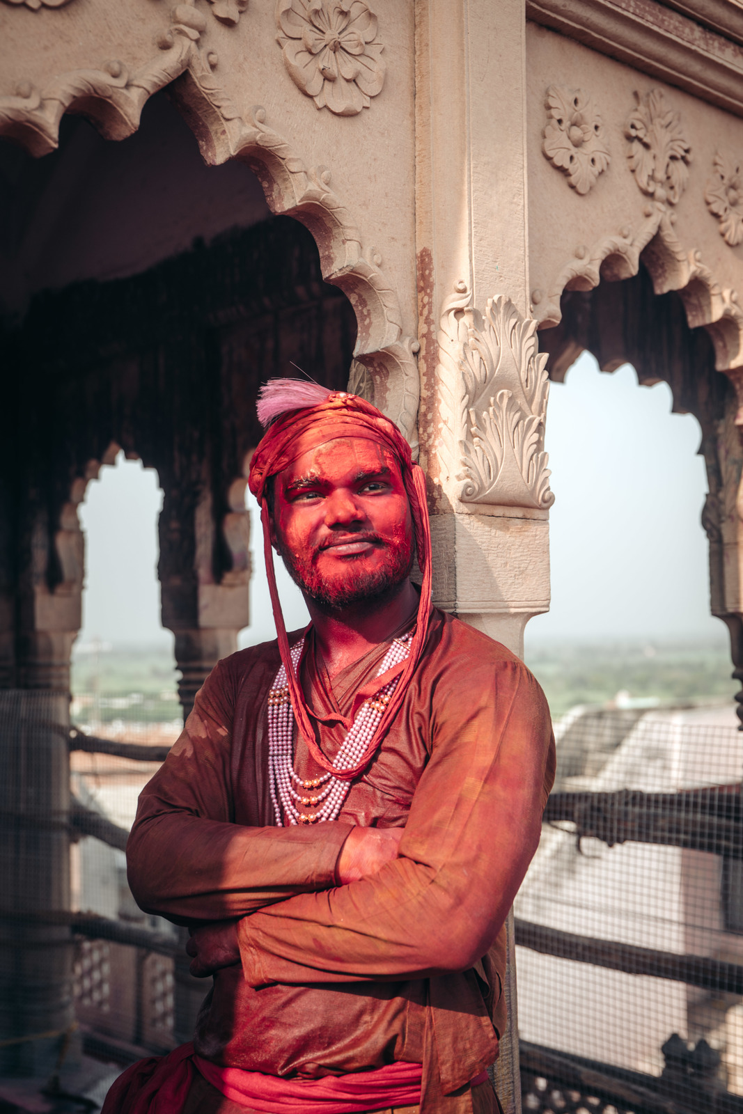 a man wearing a red turban standing in front of a building