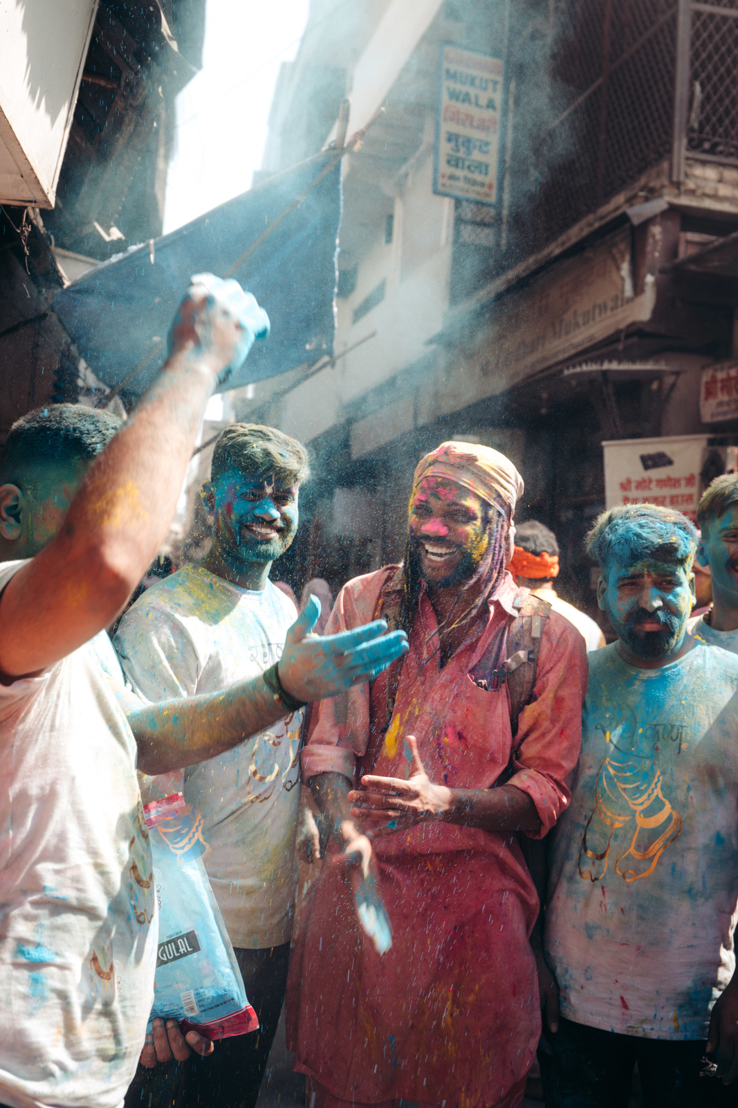 a group of people standing around each other covered in colored powder