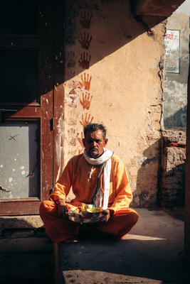 a man sitting on the ground in front of a building