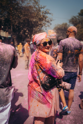 a woman covered in colored powder walking down a street