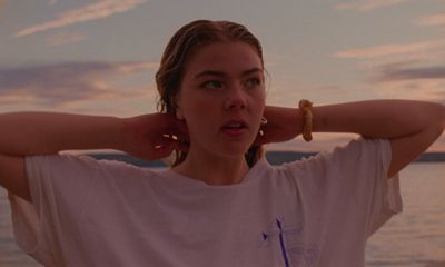 a woman standing on a beach with her hands on her ears